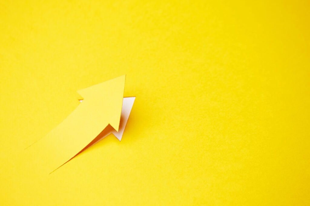Right-up arrow cutted from solid sheet of yellow paper and curved up of one side with white paper underlay showing growth of stock market or up dental practice growth